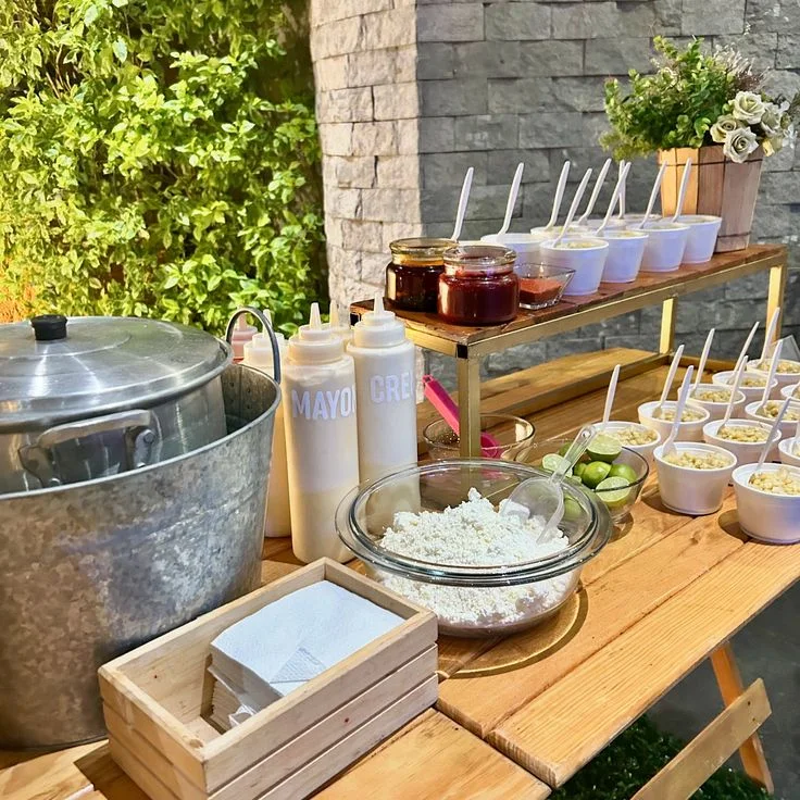Barra de esquites sobre mesa de madera en un jardín