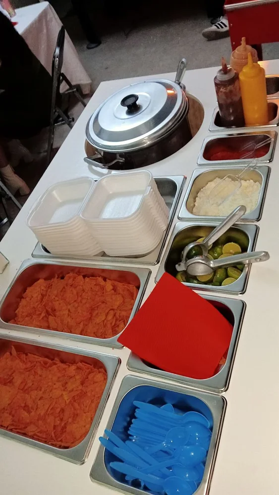 Detalle de barra de esquites con salsas, queso y limones